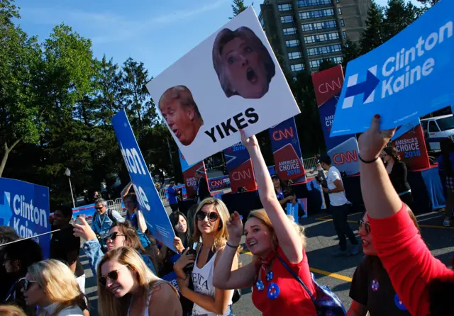 Students hold banners outside the hall where the first presidential debate at Hofstra University.