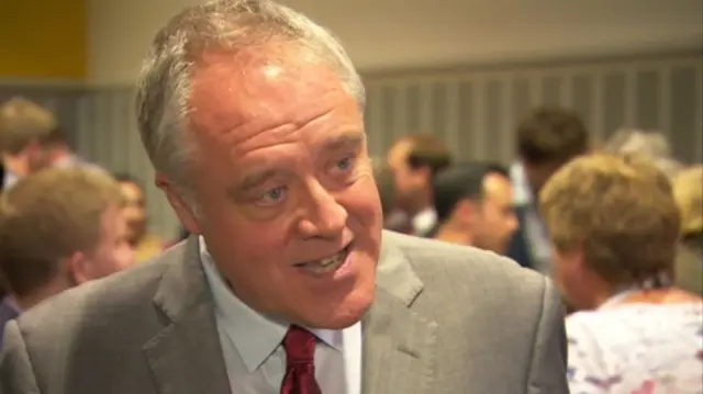 Richard Howitt MEP, in grey suit, white shirt, red tie