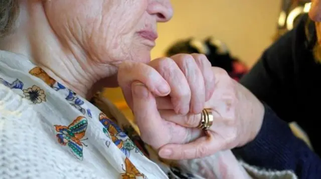 Elderly woman holding hands with other woman