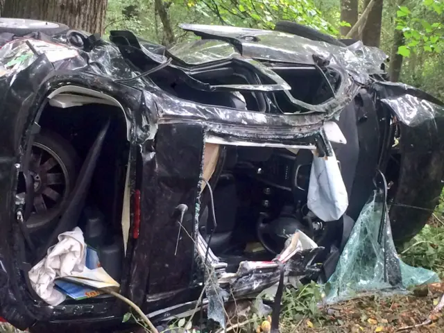 Damaged car on its side in bushes