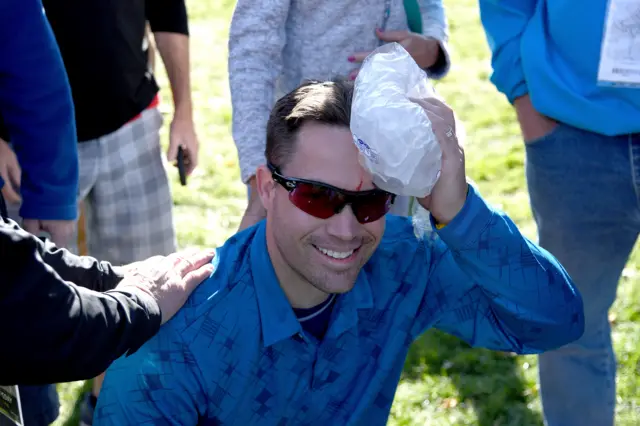 A fan holds an ice pack to his head