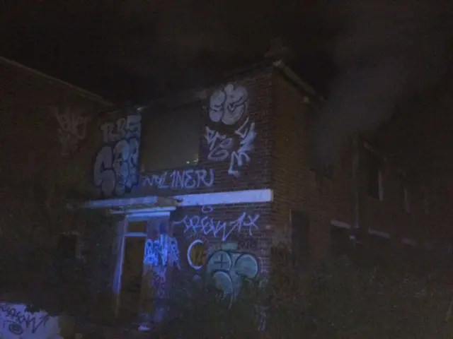 Smoke rises from a derelict building