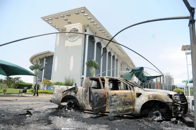 Burnt out pick-up truck in front of Gabonese government building