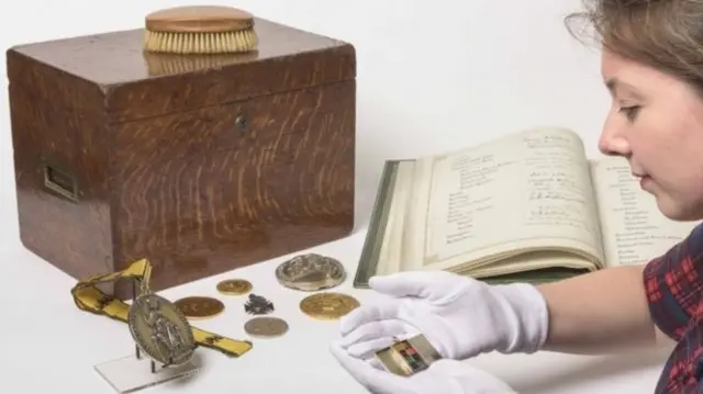 A woman looks at a book, a box and coins