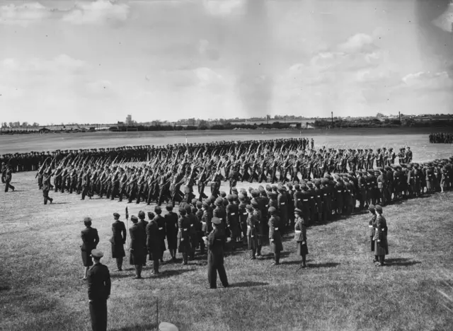 Members of the Royal Air Force march at Henlow in rehearsal for the King's Colour ceremony, whilst members of the Women's Royal Airforce look on.