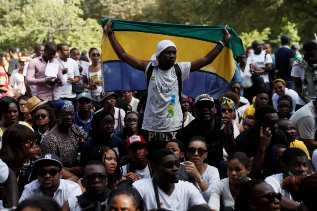 gabonese protesters in paris, one with a national flag, demonstrate