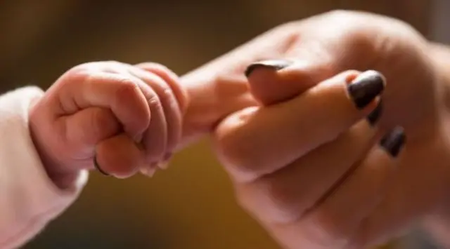 Baby clutching adults finger