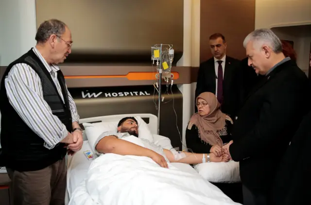 Turkish Prime Minister Binali Yildirim (R) visits a survivor of the nightclub attack at a hospital in Istanbul, Turkey, January 1, 201