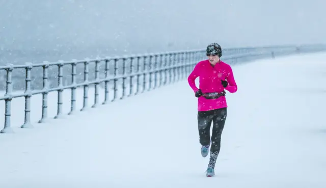 Woman running in snow in Cleethorpes, Lincolnshire