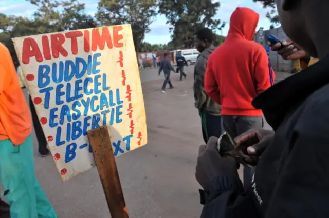 A vendor, holding US dollar notes, sells phone cards outside a market in Harare on April 14, 2010