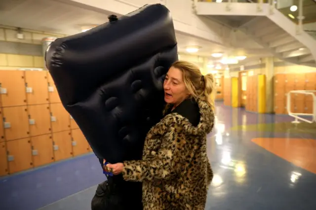 A woman carrying an inflatable bed in the rest centre in Jaywick