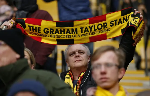 A fan holds a scarf aloft