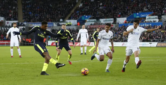 Arsenal"s Alex Iwobi shoots at goal leading to Swansea City"s Jack Cork deflecting to score an own goal