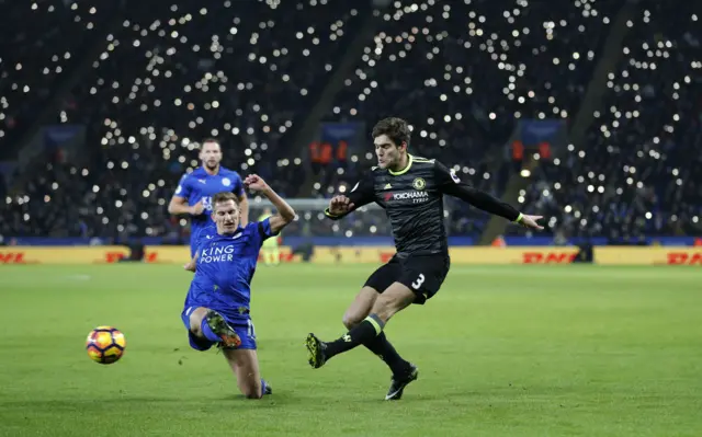 Fans light up their phones for former Chelsea and Leicester player Alan Birchenall as Chelsea"s Marcos Alonso and Leicester City"s Marc Albrighton challenge for the ball