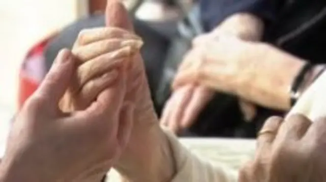 Care worker holding elderly woman's hand