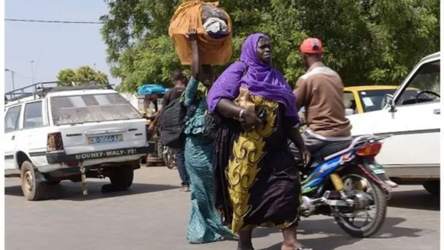 A Gambian woman carrying her luggage on the head