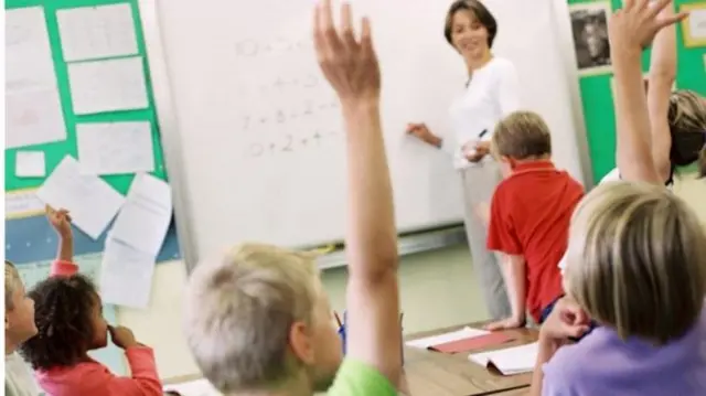 Children with hands up in classroom