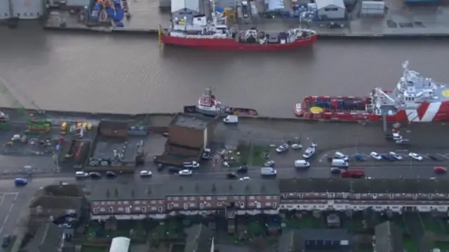 Aerial view of the River Yare, showing cargo boats, and properties opposite the rivr