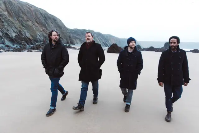 Hand-out photo of Elbow, walking on a sandy beach