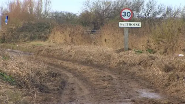 Sign for Salthouse, showing mud across metalled road