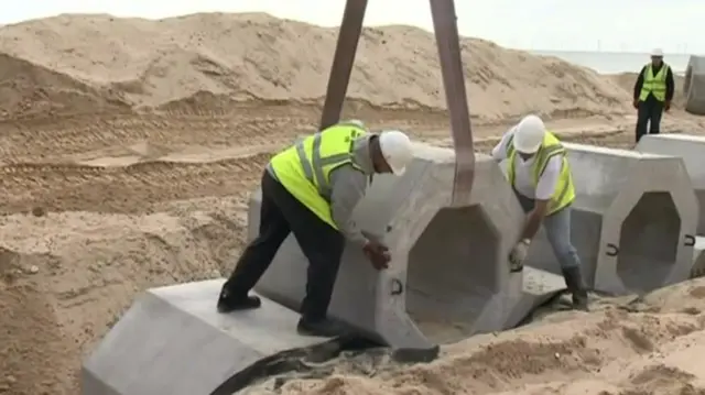 Installing the hexagonal concrete blocks into the sand