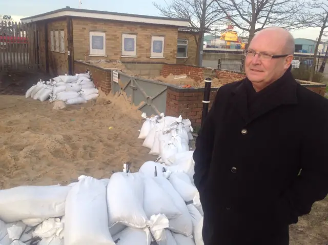 Graham Plant, standing by some sandbags