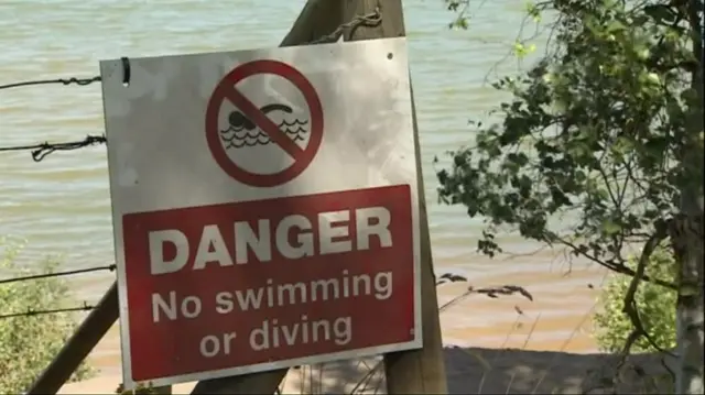 Sign warning of danger, advising no swimming or diving