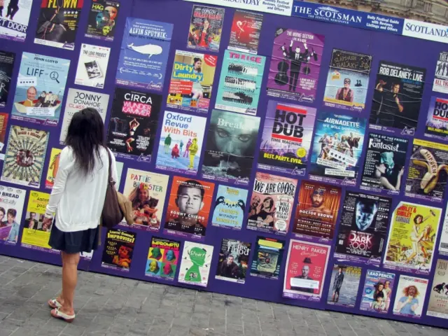 Woman looking at posters for the Edinburgh Fringe Festival