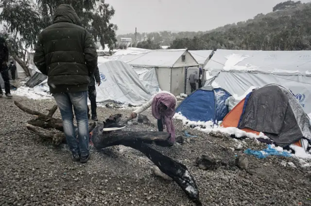 Syrian refugees on the Greek island of Lesbos, trying to light a fire during snowfall