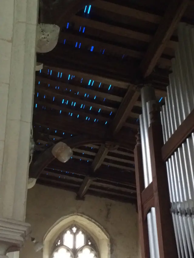 Inside Little Massingham church, looking up to the damaged roof above the organ