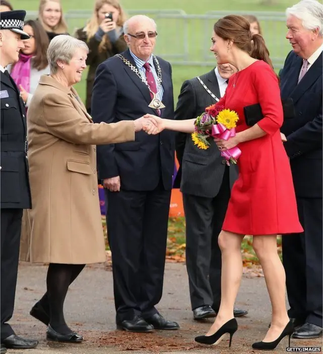 The Duchess of Cambridge, in red dress and holding small bouquet, at the launch of the appeal in November 2014