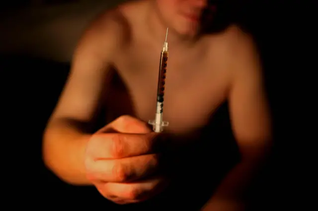 A heroin addict hlding a needle