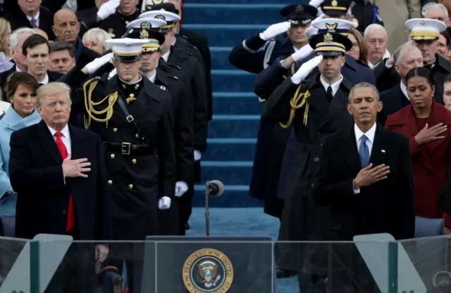 Donald Trump (left) and Barack Obama (right) listen to the national anthem