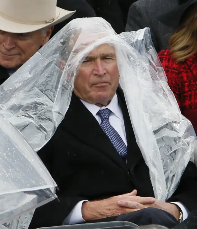 George W Bush covers himself from rain