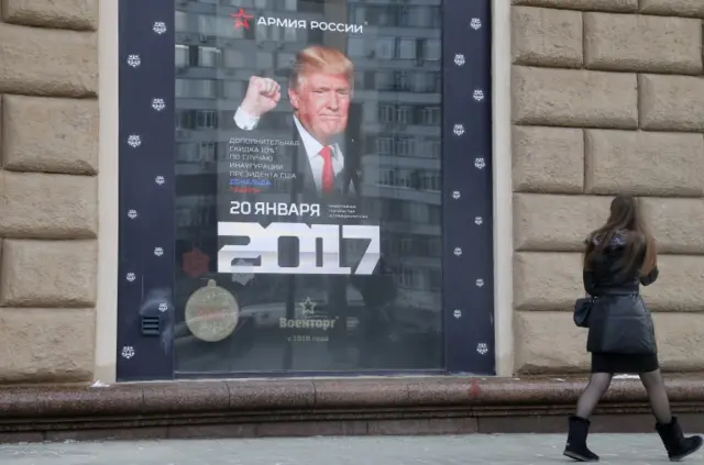 A woman walks past a Trump poster in Moscow