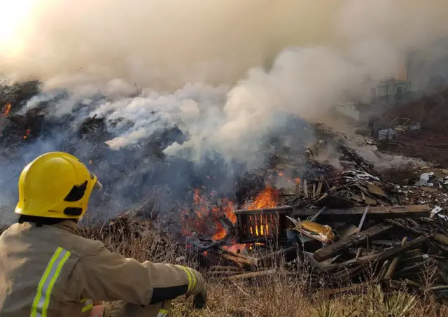 Firefighter keeping watch, over burning timber