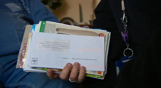 A hand holding a collection of envelopes