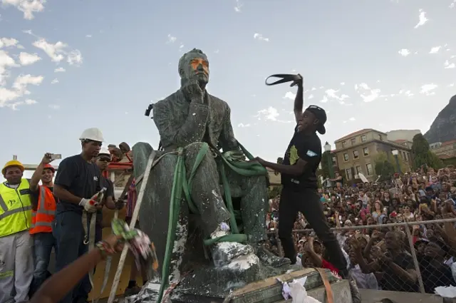 Students attack the defaced statue of British mining magnate and politician, Cecil John Rhodes, as it is removed by a crane from its position at the University of Cape Town on April 9, 2015, in Cape Town.