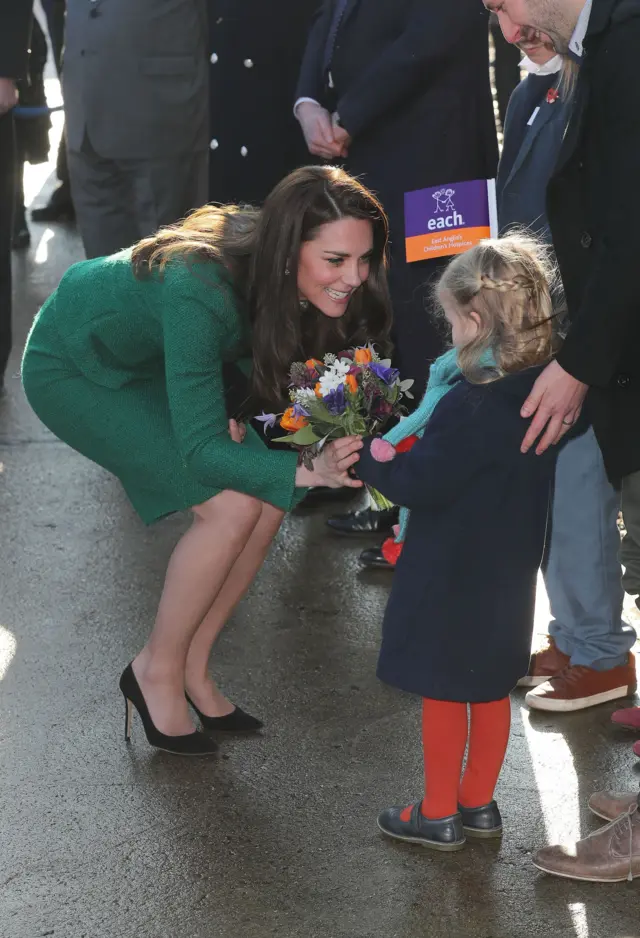 The Duchess bends down to accept a bouquet