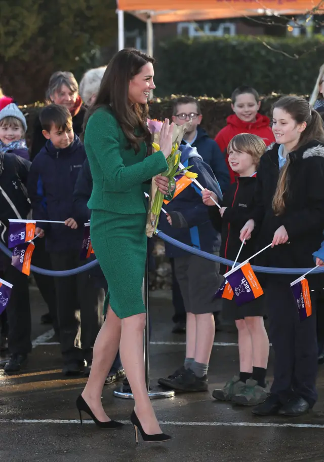 Kate in green jacket and skirt, greeting children