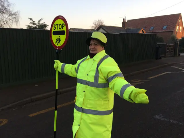 Lollipop lady, in reflective clothing, standing in road