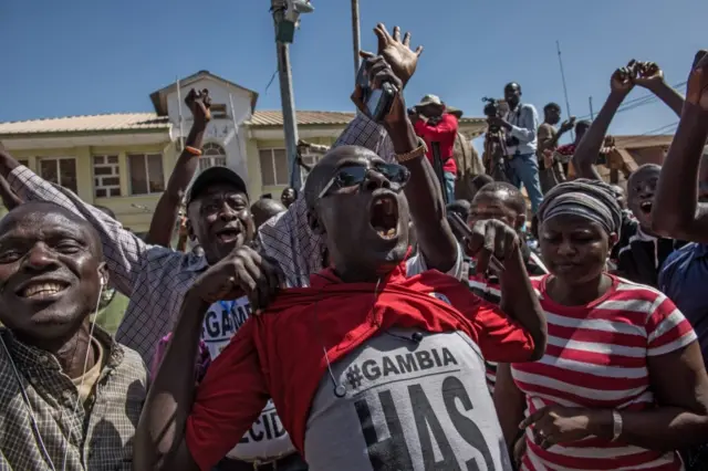 People celebrate as ECOWAS (Economic Community of Western Africa States) troops from Senegal gather outside the Gambian statehouse on January 23, 2017 in Banjul, The Gambia.