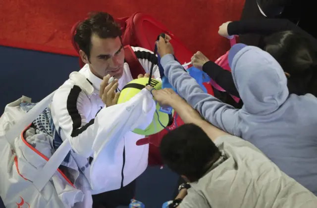 Roger Federer signs tennis balls for the fans