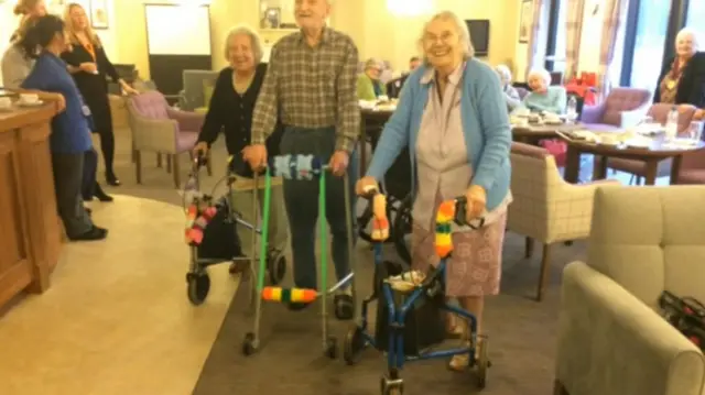 Three elderly residents standing with their decorated frames