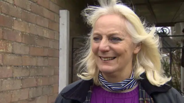 Philippa Parkin, with shoulder length blonde hair, blue striped neck scarf, purple jumper and waxed jacket