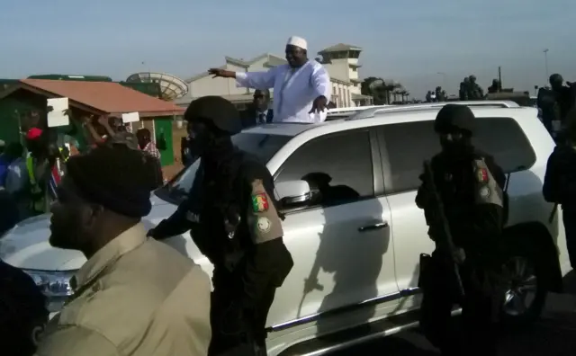 Adama Barrow waving from a car after landing in The Gambia