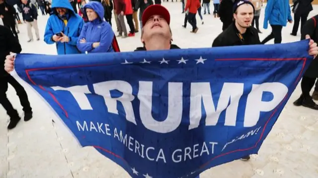 A Trump supporter waves a Make America Great Again flag