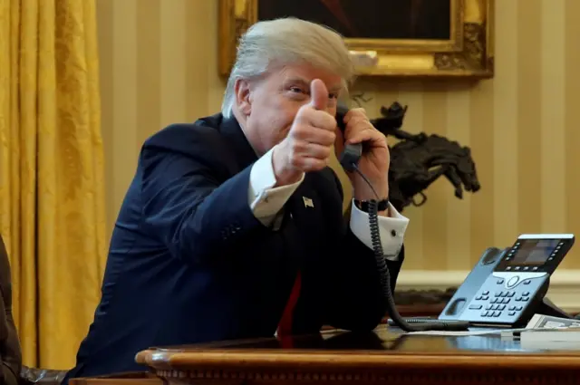 President Trump gives reporters a thumbs-up while waiting to speak to Saudi Arabia's king by phone