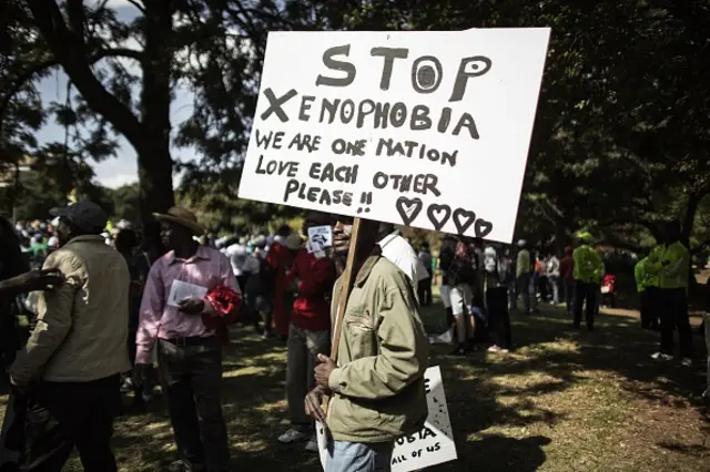 A demonstrator holds a banner through in Johannesburg on April 23, 2015 during a march gathering several thousands of people to protest against the recent wave of xenophobic attacks in South Africa.