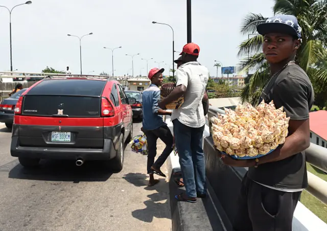 A street vendor looks on as he sells his wares on a road of Lagos on July 12, 2016.